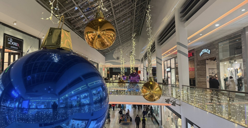 Large Christmas baubles and fairy lights hanging inside a busy Drake Circus shopping mall.